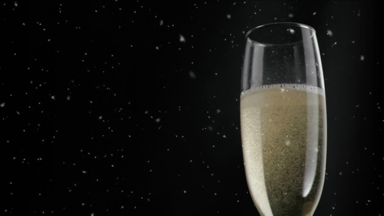 Animazione di particelle bianche che fluttuano su bicchiere di champagne su sfondo nero.