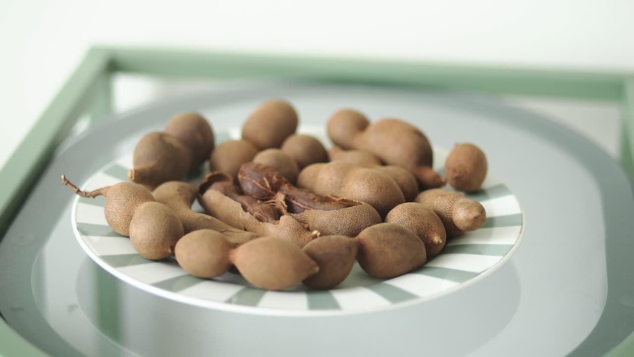 Baccelli di tamarindo freschi su un piatto a righe