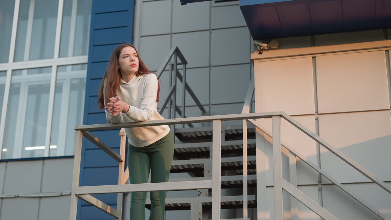 la mujer en las escaleras del edificio reflexiona sobre la depresión. la mujer joven contempla la actitud negativa hacia la vida rodeada de la serena calma de la puesta de sol.