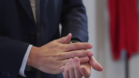 Mid-section-of-man-sanitizing-his-hands-at-office