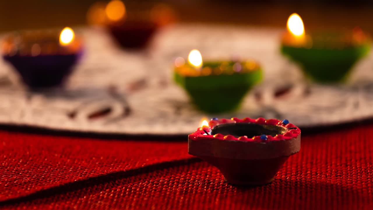 video de velas de diwali encendidas en una superficie con patrones rojos y blancos