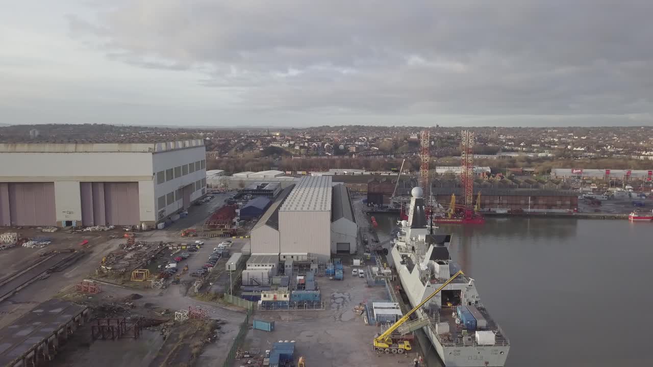 Pemandangan udara galangan kapal industri Cammell Laird Inggris yang melayani kapal perang angkatan laut dengan latar garis langit Birkenhead, geser ke kanan.