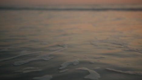 pequeñas y tranquilas olas de burbujas que lavan la arena y rompen suavemente contra la orilla