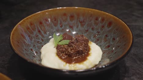 Chefs-makes-plating-of-meat-and-mashed-potato-dish,-adding-bits-of-green-veggies-nn-top