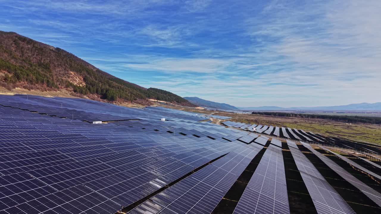 Solpaneler, der dækker land under klar himmel med fjerne bjerge