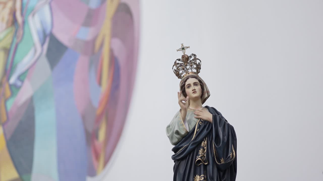crowned statue of Our Lady with hand raised in blessing beside colorful mural in Portugal