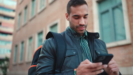 Young-man-texting-on-smartphone-outdoors.