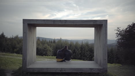 Young-couple-sit-and-lean-on-each-other-at-nature-viewpoint,-Czech-Rep