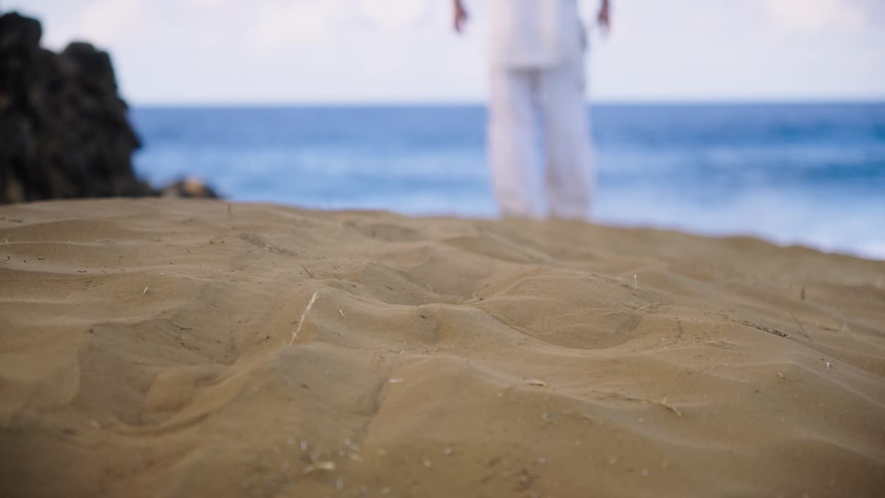 A peaceful scene of a person walking away toward the sea across soft golden sand, symbolizing serenity, solitude, and a quiet journey along the coast