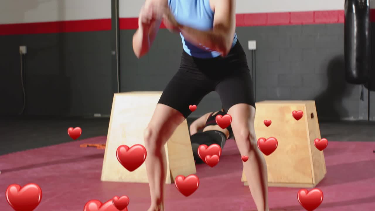 Trainer signaling, two women doing box jumps and burpees for fitness, red heart overlaying trio
