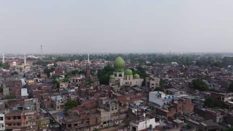 cinematic aerial view above mosque in crowded urban city. dense downtown cityscape