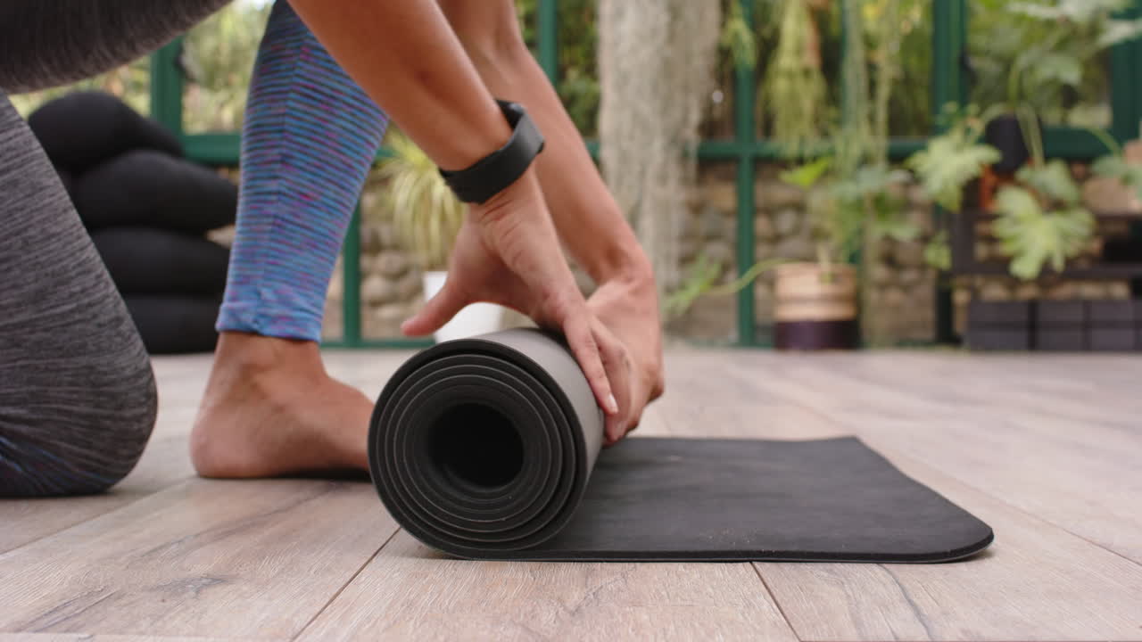 Rolling up yoga mat, person finishing outdoor yoga session in garden