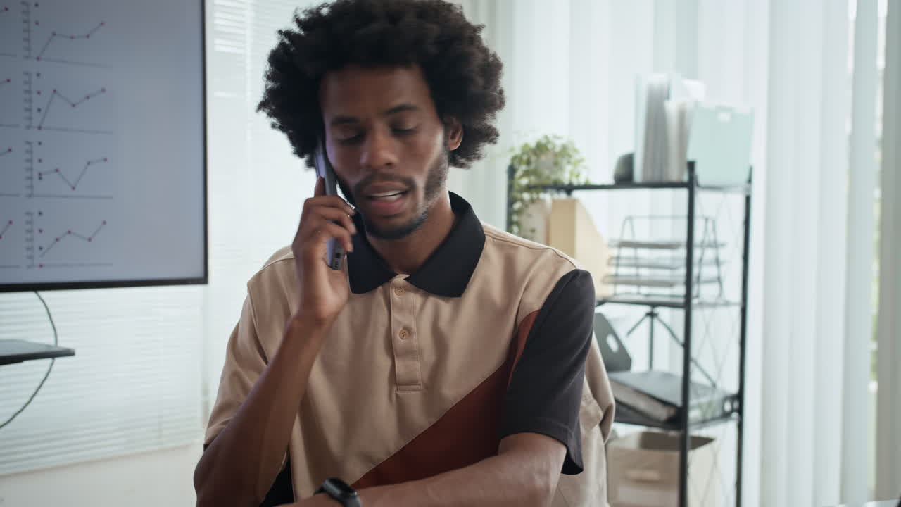 Empreendedor falando ao celular com sócios em frente ao laptop