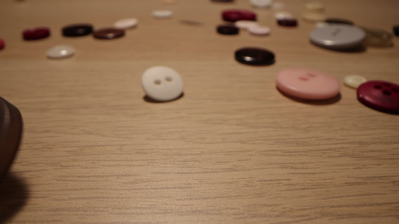 Sewing buttons falling on a wooden background. Clothes colorful buttons fall on wooden tabl
