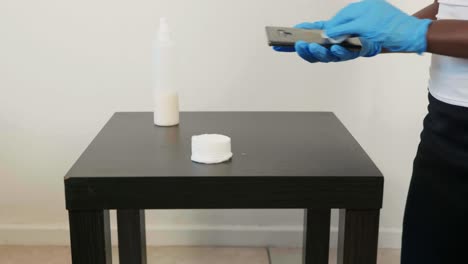 african lady disinfects phone wearing gloves during covid19