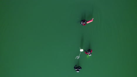 Toma-Aérea-Baja-Sobre-La-Cabeza-De-Un-Grupo-De-Buzos-Entrenando-En-El-Lac-Du-Crès,-Francia