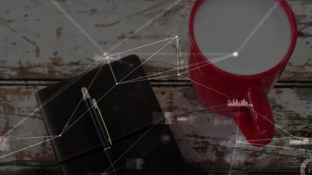 Rustic wooden tabletop featuring frothy red mug and bound leather notebook with digital overlay