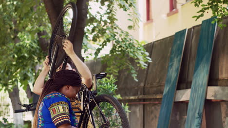 sporty couple repairs bicycle in yard