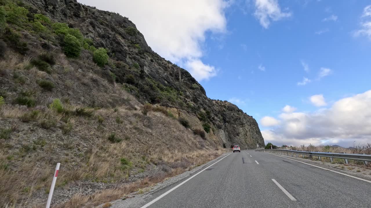 Vehicle travels winding mountain road, scenic landscape, daylight, wide angle, smooth forward camera movement