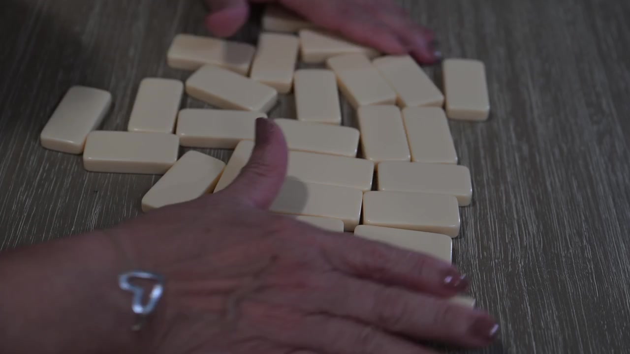 Mani di donna anziana che mescolano i domino all'inizio di una partita.