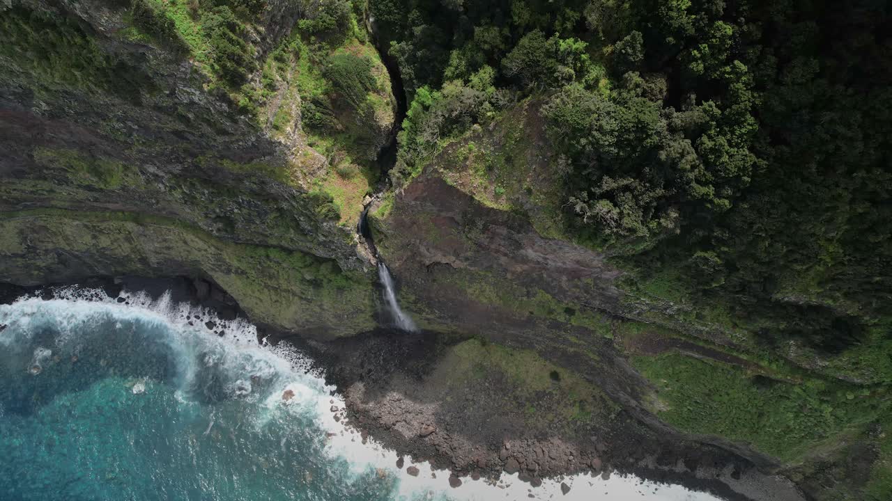 Madeira Véu da Noiva viewpoint aerial view looking down descending steep rock face towards waterfall cascading into ocean below