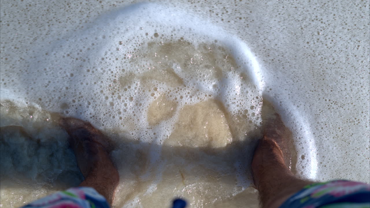 멕시코 칸쿤 파도에 젖어 카리브해 해변의 모래 위에 서 있는 라틴 남자의 슬로우 모션 pov