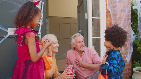 Grandchildren-Dressing-Up-And-Visiting-Grandparent's-House-Trick-Or-Treating-On-Halloween