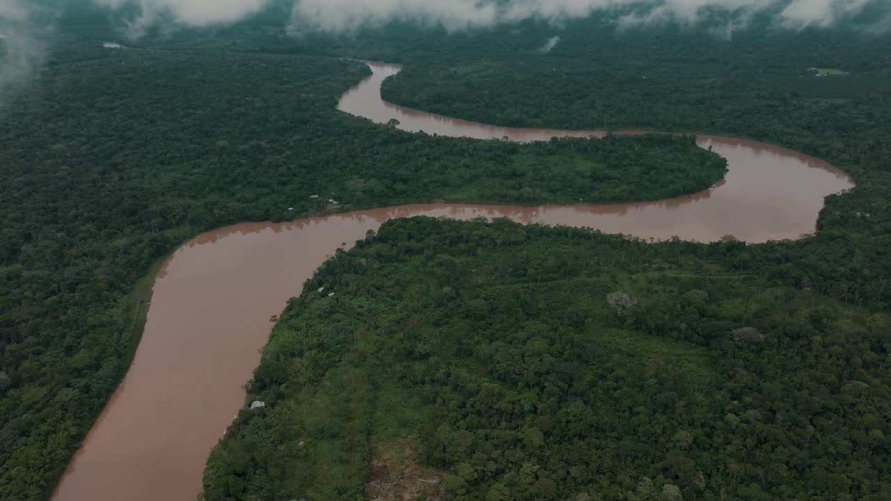 toma aérea inclinada hacia arriba que muestra el tranquilo río amazonas de color marrón flotando entre la jungla de sudamérica - cielo nublado en el desierto
