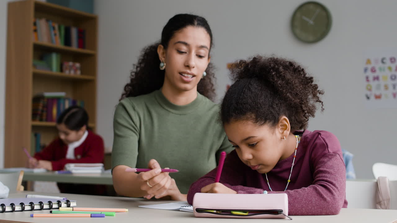 Teacher helping a student with homework in a classroom.
