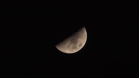 half-moon slowly moving across a dark black night sky