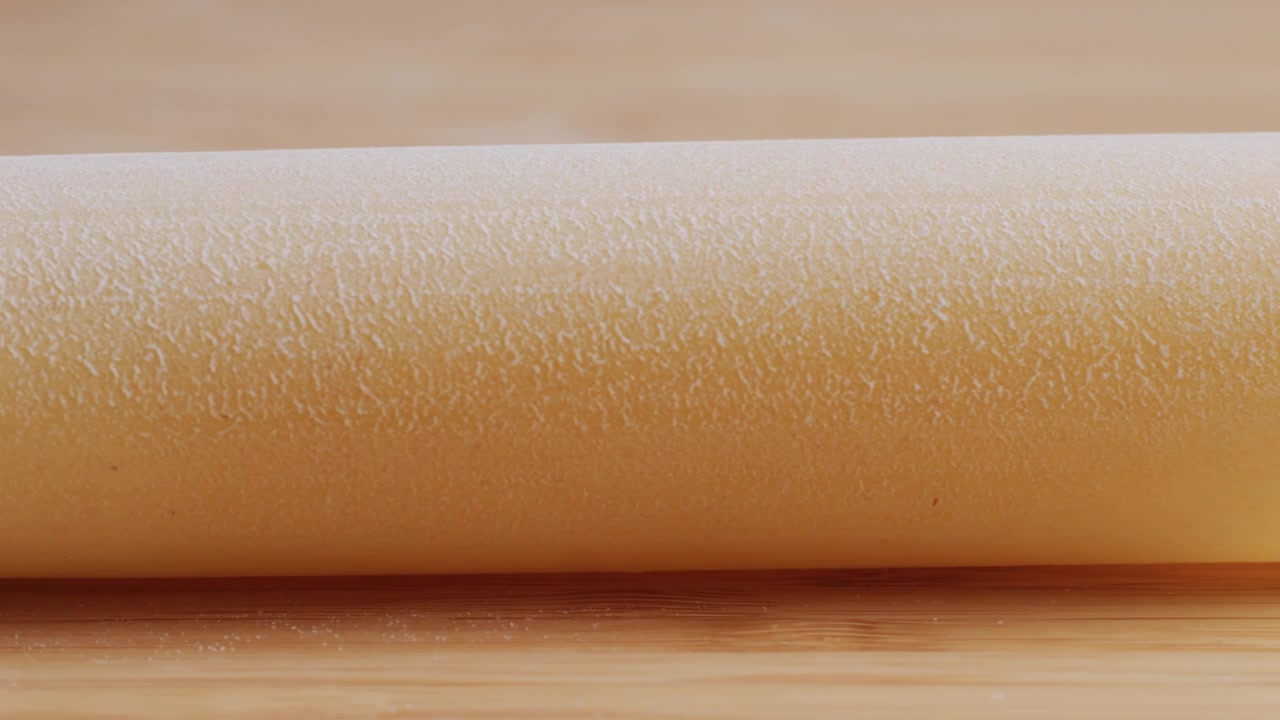 Lenta panoramica su impasto crudo coperto di farina bianca su una superficie di legno