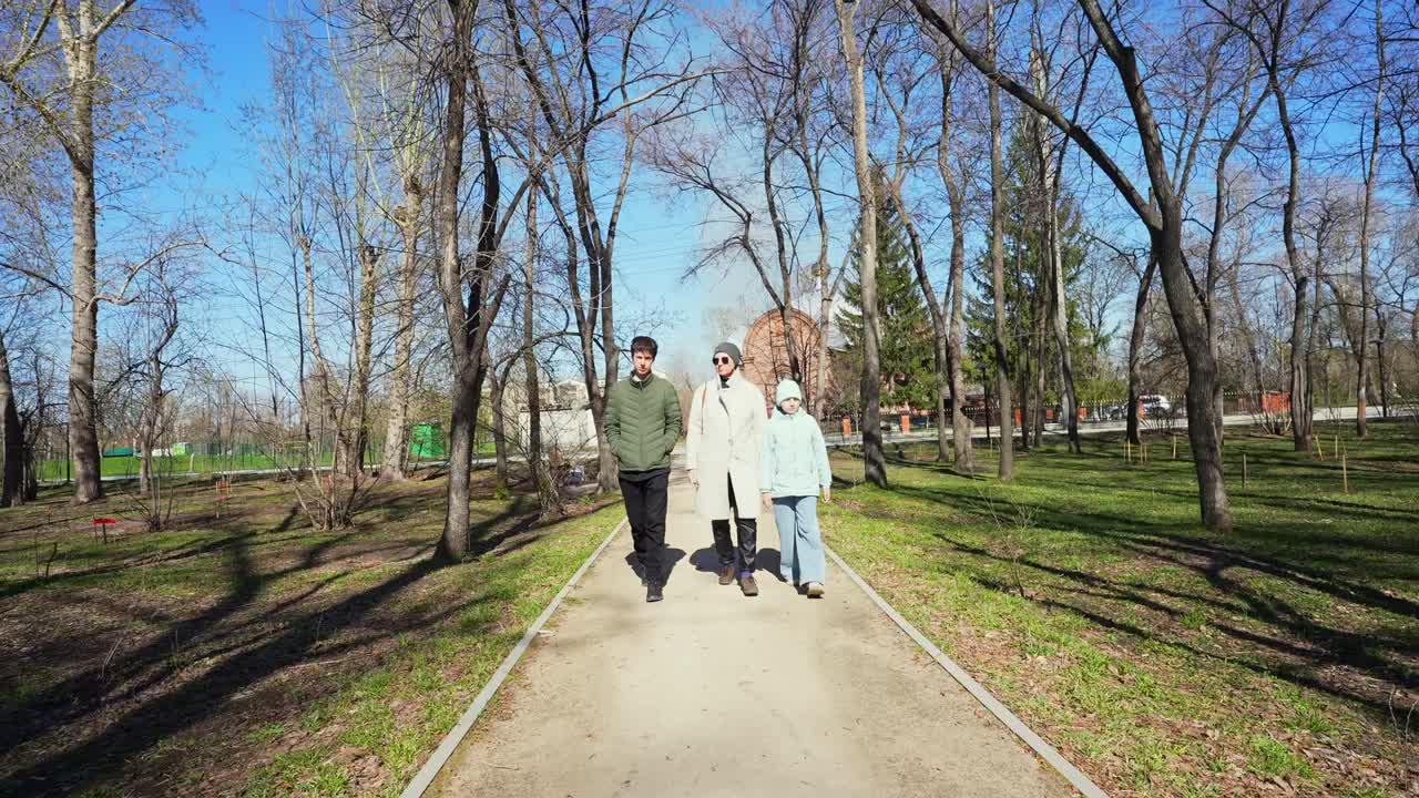 Tres personas caminando juntas por un sendero en un parque.
