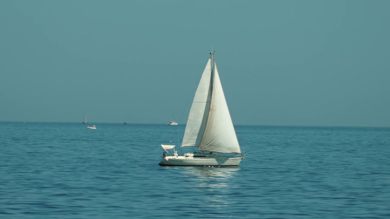 Barca a vela su un vasto oceano blu aperto, che si muove con grazia sotto un cielo sereno, incarnando viaggio, libertà e avventura pacifica, Golfe Juan, Francia.