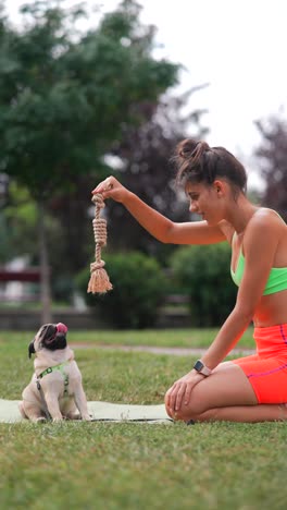 woman playing with a pug puppy in a park