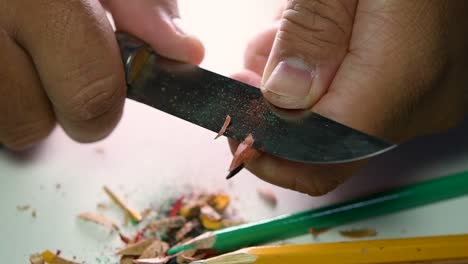 Footage-of-hands-slowly-sharpening-a-pencil-and-some-coloured-pencils-with-a-sharp-knife