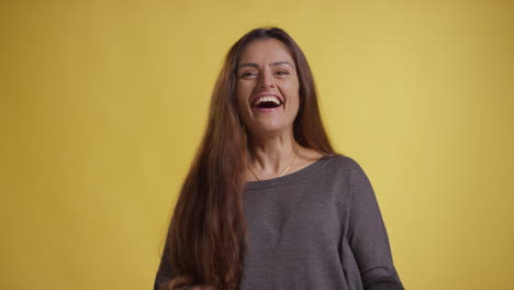 retrato de estudio de una mujer emocionada celebrando buenas noticias de pie contra un fondo amarillo