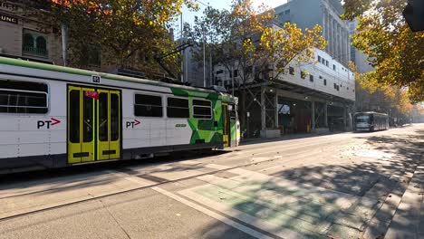 a tram moves along a sunny melbourne street