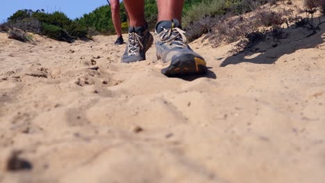 ground level view of two hikers walking past camera in golden sand