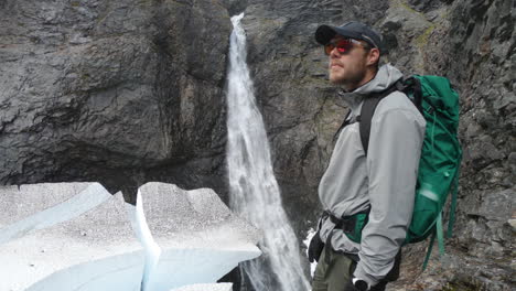 male hiker with sunglasses looking at the famous waterfall, silverfallet, northern sweden