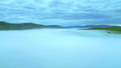 flying high over fog bank with cloudy sky and distant mountains at dawn