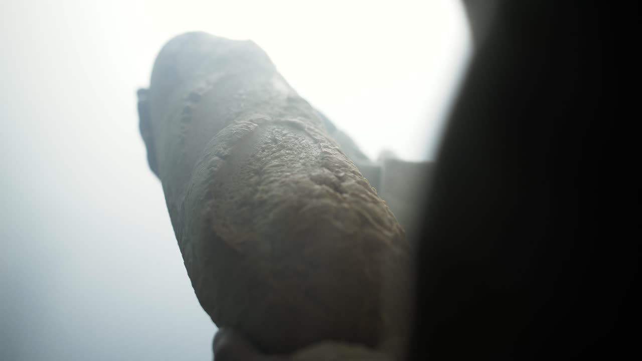 Jesus Christ in white robe and glowing light holding bread as a representation of the gospel and Jesus as the bread of life in cinematic, dramatic slow motion.