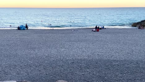 People-Sitting-On-The-Rocky-Shore-Of-Magnan