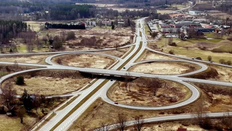 Drone-fly-above-highway-junction-traffic-at-Latvian-rural-countryside-village