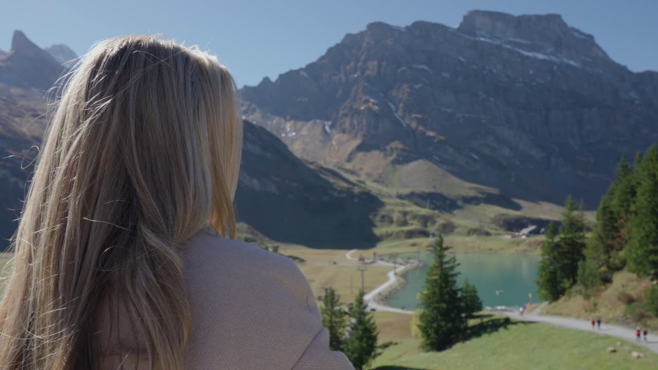 Woman enjoys view of clear lake in a beautiful mountain setting on a sunny day in Engelberg, Switzerland