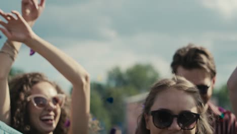 young caucasian friends dancing among confetti on music festival with hands up.