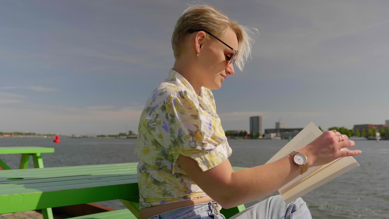 아름 다운 젊은 여자는 피크닉 테이블에서 책을 읽습니다