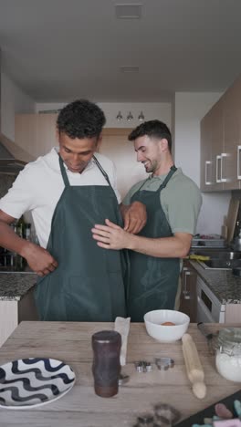 Two Men Putting on Aprons in Kitchen