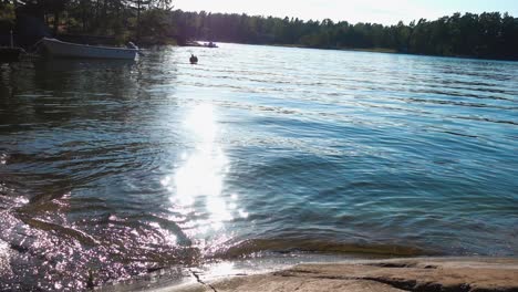 Wasser,-Das-In-Der-Sonne-Glitzert,-Mit-Einem-Boot-Im-Hintergrund