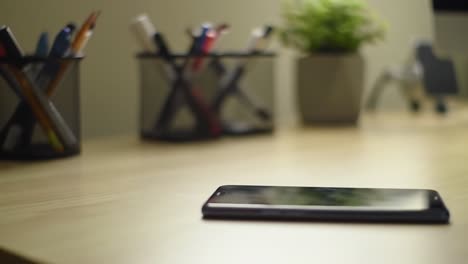 a close-up view of an organized workspace featuring writing utensils, a smartphone, and a potted plant for an aesthetic touch