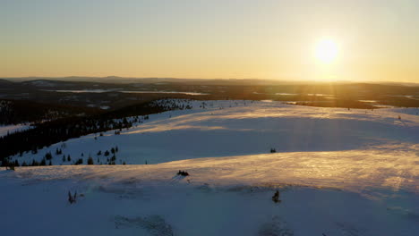 Vista-Aérea-A-Través-Del-Impresionante-Paisaje-De-Colinas-Y-Valles-Nevados-De-Laponia-Iluminada-Por-El-Sol-Del-Amanecer